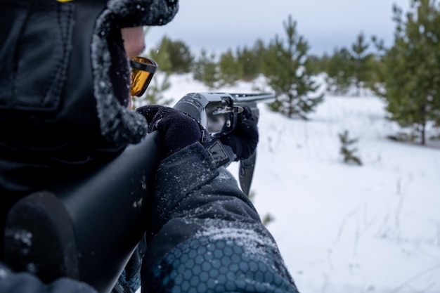 Hunter with a gun in the winter forest