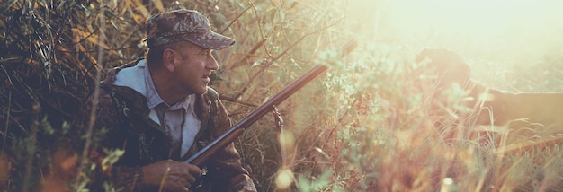 Hunter with a hat and a gun in search of prey in the steppe Aims for prey Panoramic image for your text toned