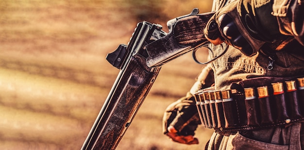 Hunter with a hunting gun and hunting form to hunt in an autumn forest. The man is on the hunt. Hunter with a backpack and a hunting gun.