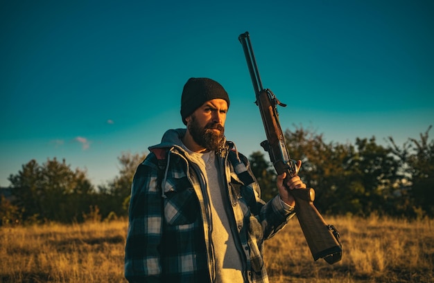 Hunter with shotgun gun on hunt bearded hunter man holding gun and walking in forest