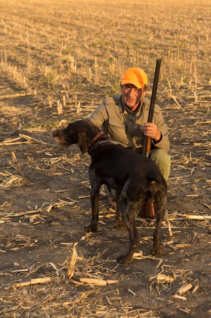 ドイツのドラサーとスパニエルを持ったハンター、反射ベストを着た犬との鳩狩り