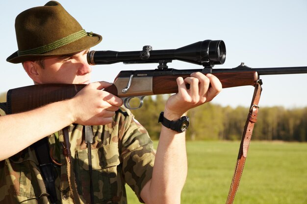 Premium Photo Hunting gun scope and man hunter on africa safari in grass for shooting animals on holiday weapon sniper and male person aim for wild game in nature with mockup
