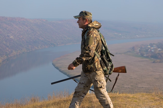 사냥 기간 가을 시즌 오픈 사냥복을 입고 손에 총을 든 사냥꾼