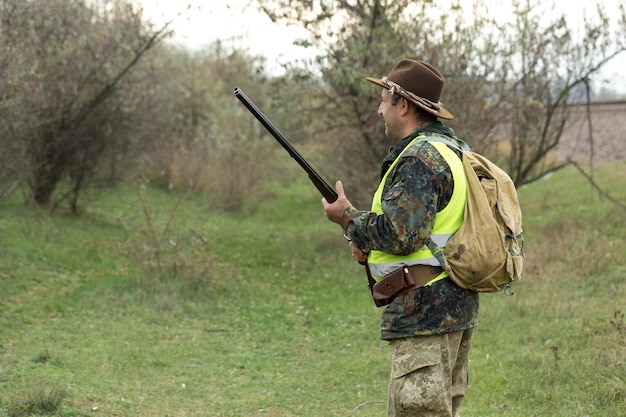 Hunting period autumn season open A hunter with a gun in his hands in hunting clothes in the autumn forest in search of a trophy A man stands with weapons and hunting dogs tracking down the game