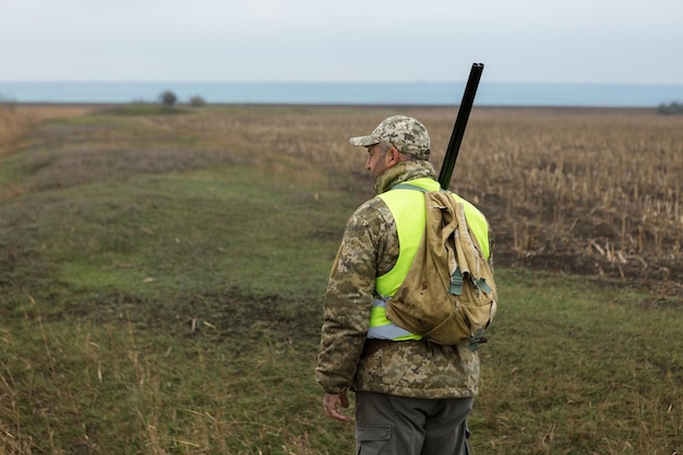 Hunting period autumn season open A hunter with a gun in his hands in hunting clothes in the autumn forest in search of a trophy A man stands with weapons and hunting dogs tracking down the gamex9xA