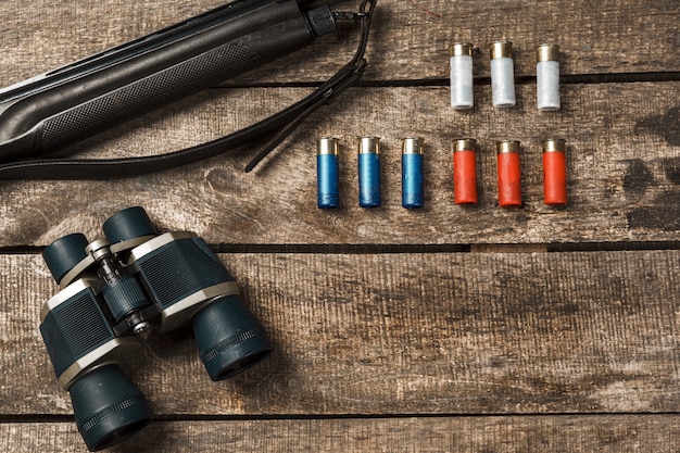 Hunting rifle and binoculars on dark wooden background