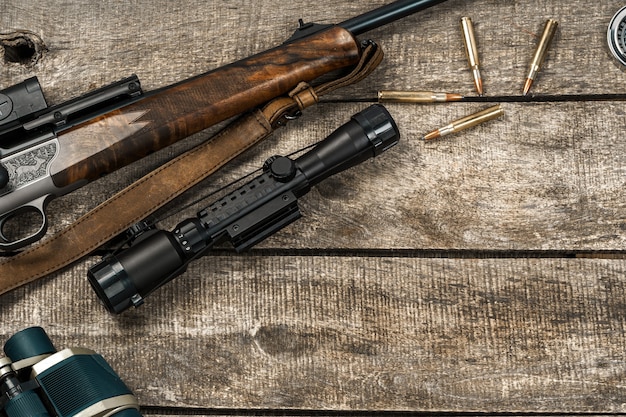 Hunting rifle and cartridges on dark wooden background