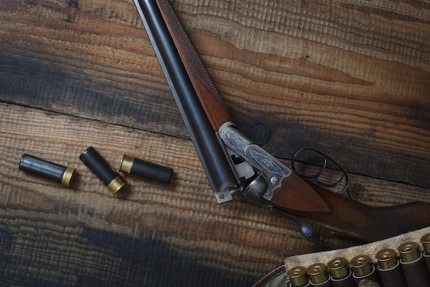 Hunting rifle and hunting accessories on the table Vintage hunting gun with cartridges on wooden background Top view