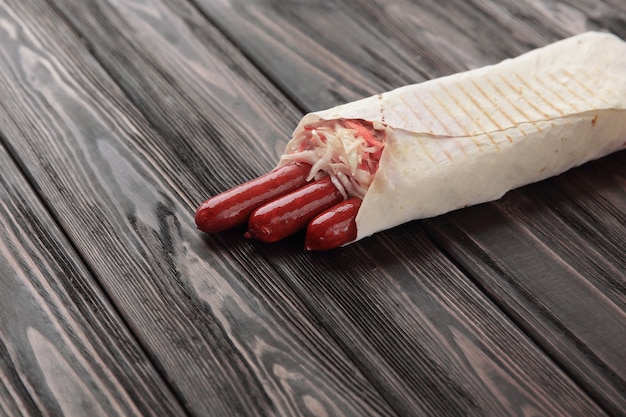 Hunting sausages in pita bread on a dark wooden background.