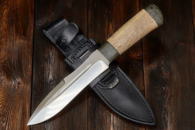 Hunting steel knife handmade on a wooden surface, close-up