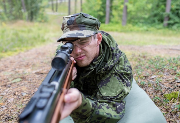 狩猟、戦争、軍隊、人々の概念-森の中で銃を持った若い兵士、レンジャー、ハンターのクローズアップ