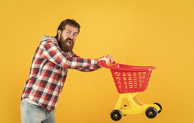 Hurry up shopaholic in shop or store buy and purchase mature guy in checkered shirt go shopping stylish male carry shopping cart bearded man with moustache on unshaven face householding