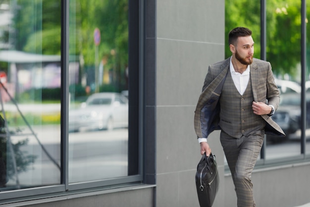 Hurrying to work. Full length of young businessman looking forward while running along the street