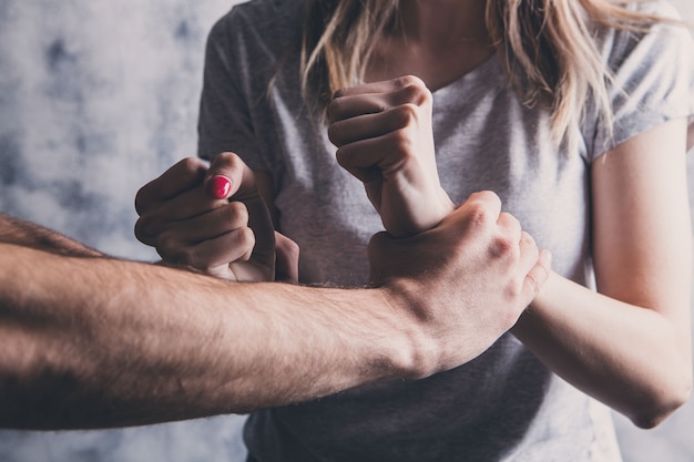 Photo husband assaulting his wife on a gray