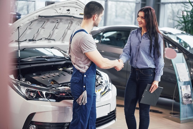 Photo husband car mechanic and woman customer make an agreement on the repair of the car