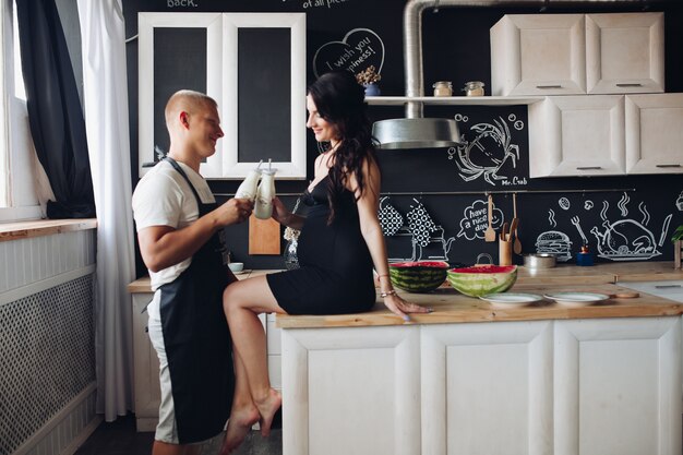 Husband cooking dinner for adorable pregnant wife at home