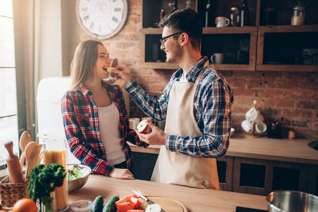 Husband feeds wife a banana on the kitchen