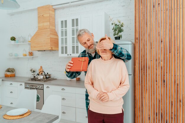 Photo husband gives a gift to her wife at home