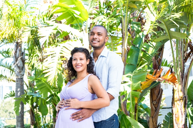 Husband looking away while touching pregnant wife belly