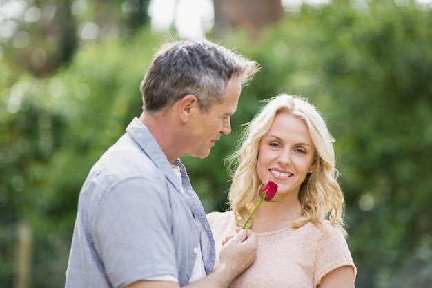 Муж предлагает жене розу на улице в лесу