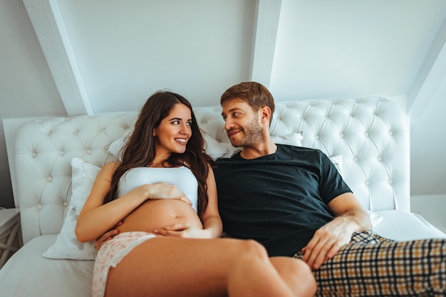 Husband and pregnant wife sitting together in a bedroom