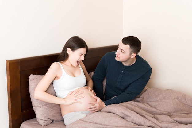 husband shocked while his pregnant wife has contractions on bed in home