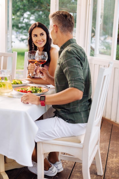 Husband wearing smart watch drinking wine with beautiful wife