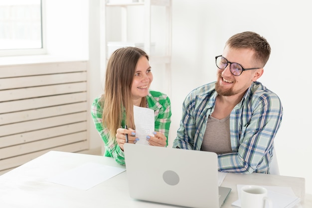 Husband and wife discuss amount in check for payment of the apartment and compare it with the rates on official website while sitting at the table with laptop. Concept of payment of utility bills.