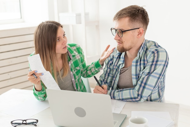 남편과 아내는 노트북으로 테이블에 앉아 아파트 지불에 대한 수표 금액을 논의하고 공식 웹 사이트의 요금과 비교합니다. 유틸리티 요금 지불의 개념입니다.