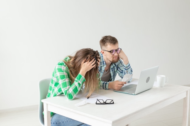 Husband and wife discuss amount in check for payment of the apartment and compare it with the rates on official website while sitting at the table with laptop. Concept of payment of utility bills.