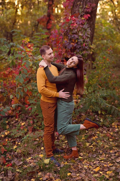 Husband and wife hug each other outdoors in autumn