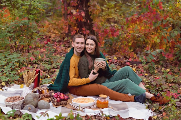 夫と妻は自然の中でピクニックでお互いをハグします。