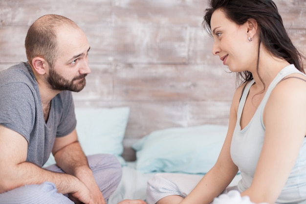 Photo husband and wife wearing pajamas looking at each other after waking up in the morning.