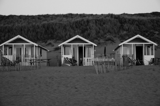 Hut on beach by houses against sky