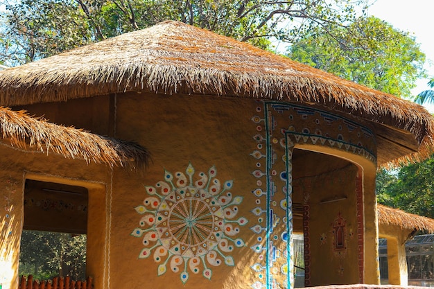 A hut with a thatched roof and a floral design on the roof