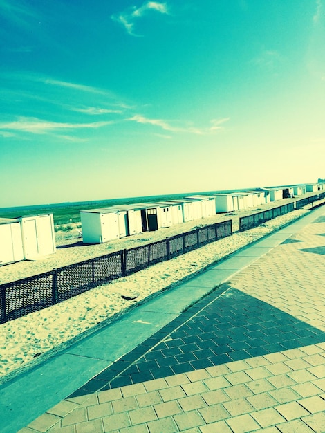 Foto capanne sul sentiero sulla spiaggia di sabbia contro il cielo