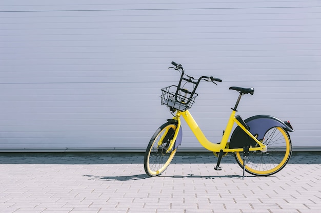 Huur een fiets, een gele fiets staat tegen een grijze muur.