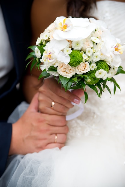 Huwelijksboeket en handen met ringen