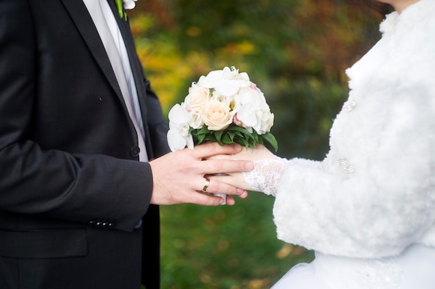 Huwelijksboeket en handen met ringen