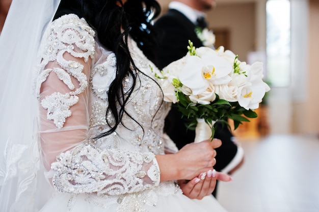 Huwelijksboeket van witte orchideeën op hand van bruid op kerkceremonie