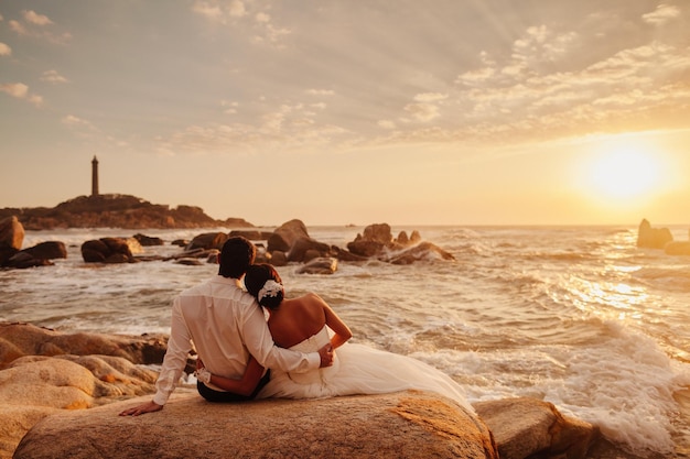 Huwelijksreis paar ontspannen op zonsondergang strand Uitzicht op zee met vuurtoren