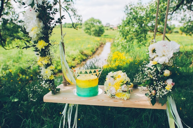 Huwelijksschommeling die met bloemen wordt verfraaid die op de takken van de oude wilg hangen