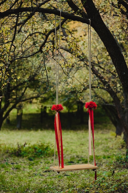 Huwelijksschommeling die met bloemen wordt verfraaid die op de takken van de oude wilg hangen