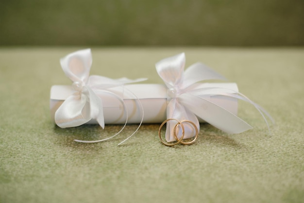 Huwelijksuitnodiging met een rietje met witte strikken en trouwringen