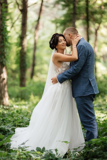 Huwelijkswandeling van de bruid en bruidegom in het loofbos in de zomer