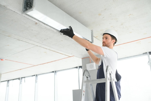 사진 hvac 엔지니어가 새로운 집 복사 공간에 열 회수 환기 시스템을 설치합니다.