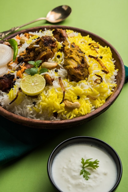 Hyderabadi chicken or dum biryani, served in a Kadhai or bowl with yogurt dip . selective focus