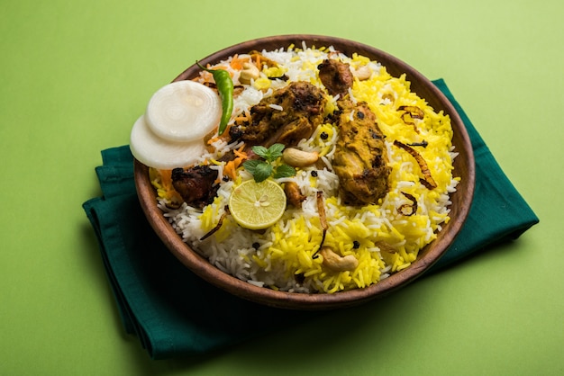 Hyderabadi chicken or dum biryani, served in a Kadhai or bowl with yogurt dip . selective focus