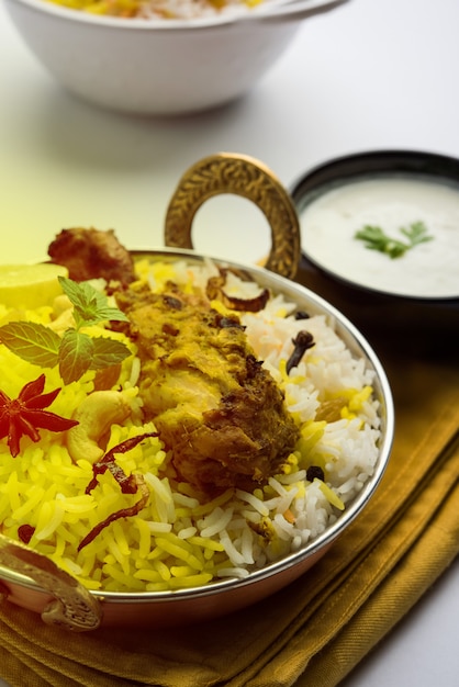 Foto pollo hyderabadi o dum biryani, servito in un kadhai o in una ciotola con salsa allo yogurt. messa a fuoco selettiva