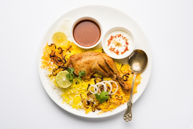 Hyderabadi chicken or dum biryani, served in a Kadhai or bowl with yogurt dip . selective focus